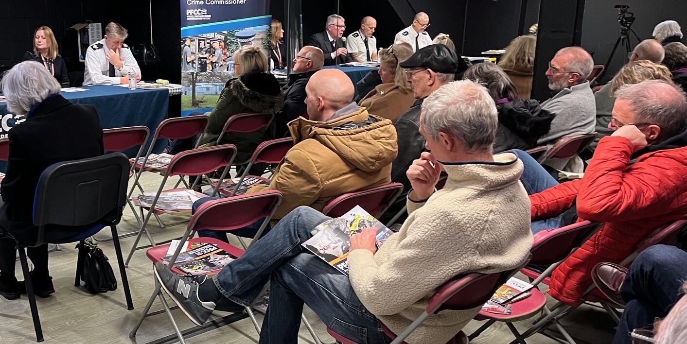 people sitting in chairs at a public meeting