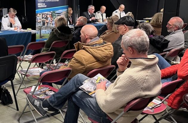 people sitting in chairs at a public meeting
