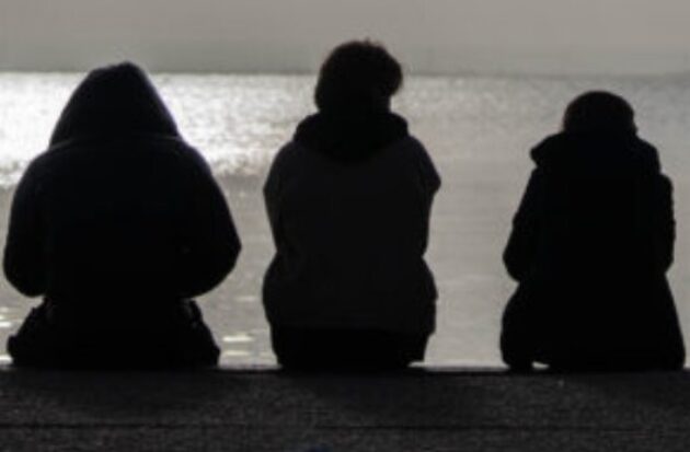 Young people sitting watching the sea