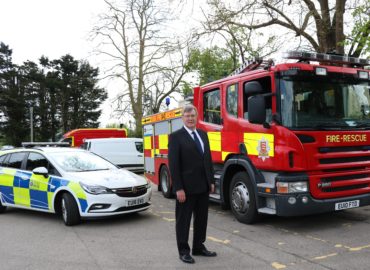 PFCC Roger Hirst standing in front of a police car and a fire engine.