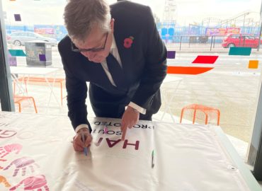 PFCC Roger Hirst writing his message on the Hands Together banner.