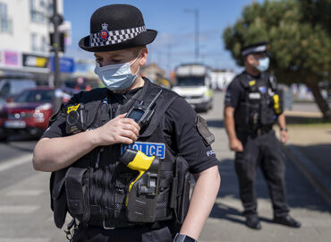 A police officer wearing a face mask talks into their radio whilst on patrol on Southend seafront.